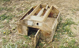This old type of wooden brooder uses a kerosene stove or an alcohol lamp in the inner compartment to heat the small pipes on top. Chicks rest directly below the pipe.